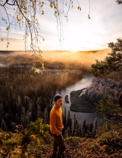 Lapin valokuvaaja Suomen Lapissa sumuisen jokilaakson yllä auringonnousun aikaan.